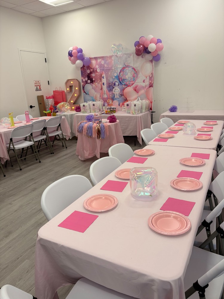 Pastel pink and purple party: balloon garland over a decorated backdrop with long tables set in blush pink