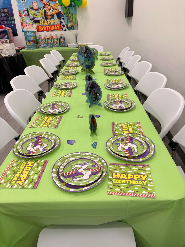 Toy Story tablescape: long green table with themed plates, napkins and dinosaur centerpieces
