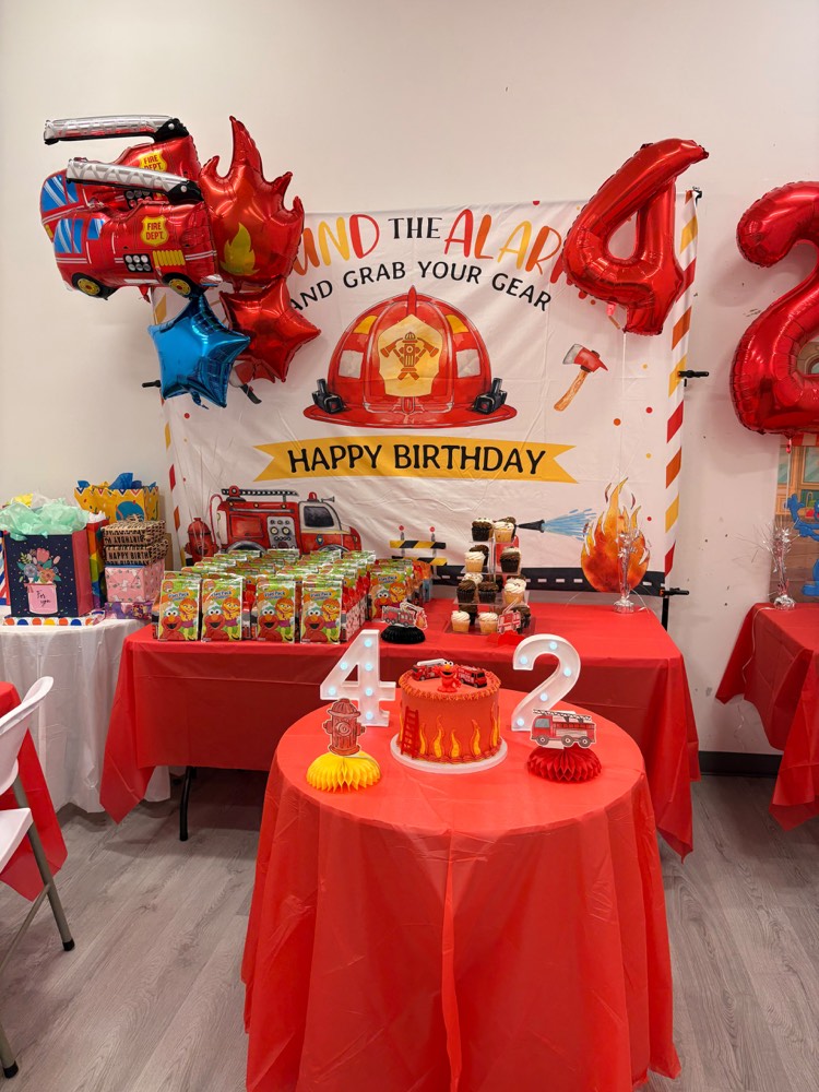 Firefighter party: Sound the Alarm backdrop, fire truck balloon, red number four balloons and red tables