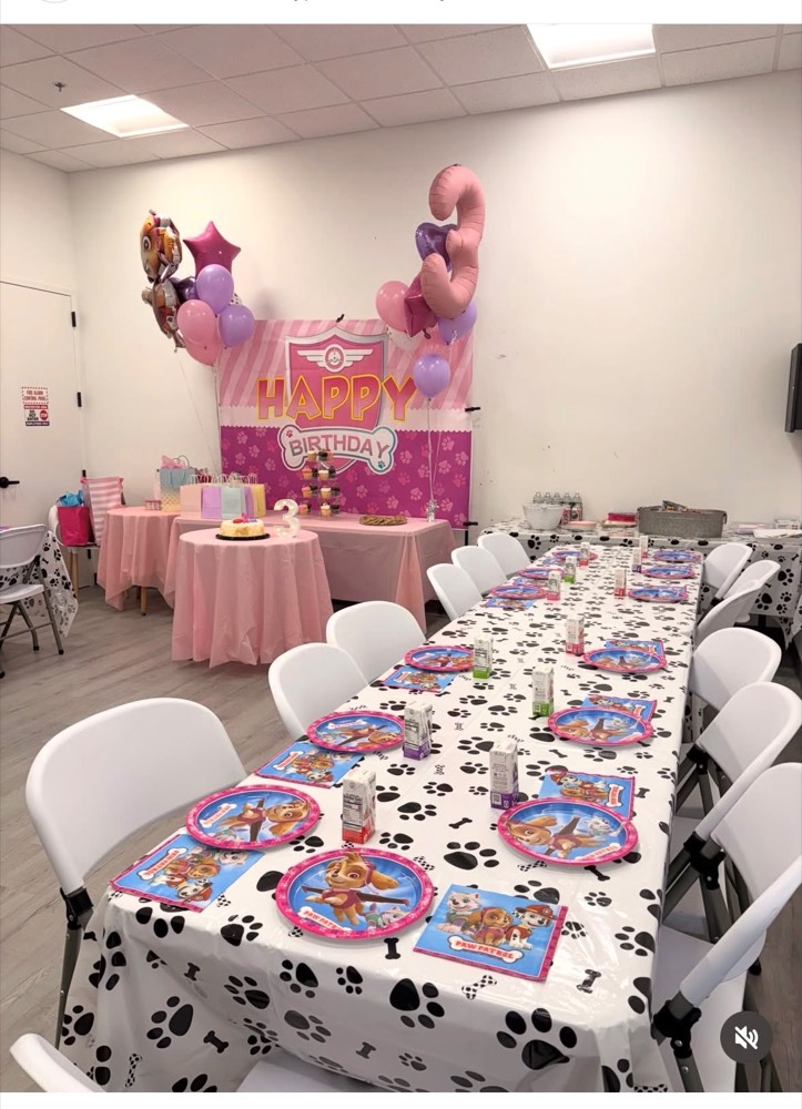 Paw Patrol party in pink: paw print tablecloth, pink balloon arch and themed place settings