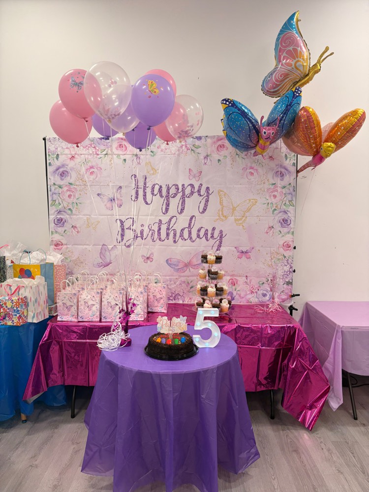Butterfly and floral party: purple and pink backdrop with butterfly balloons and a cupcake tower