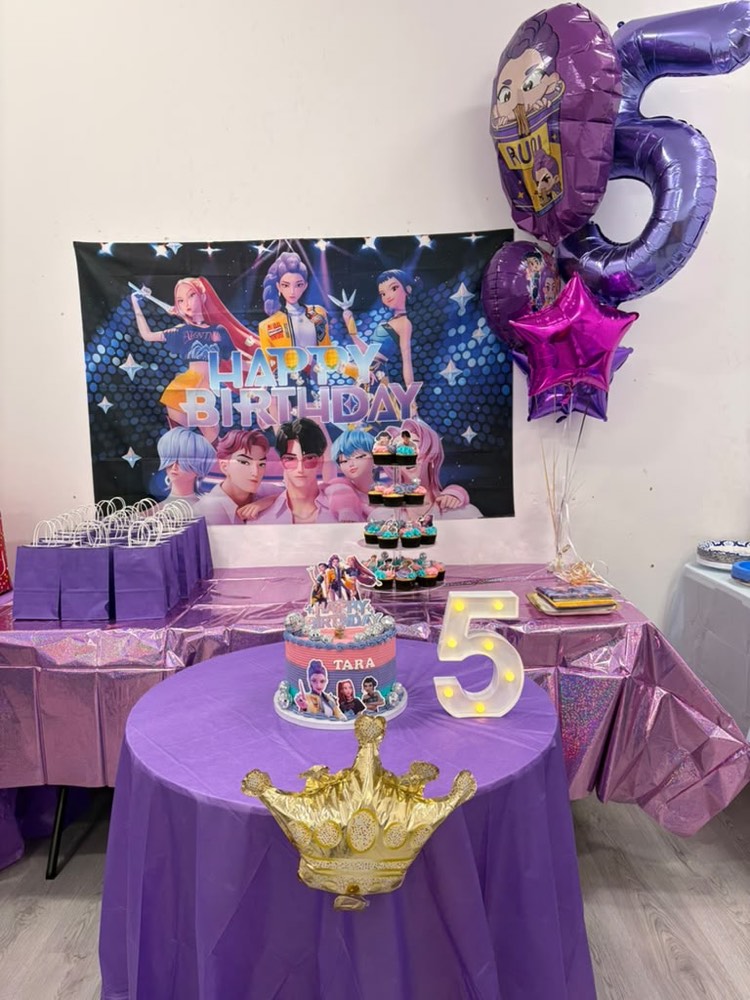Pop star themed party: glittery backdrop, purple number five balloon, gold crown and decorated cake