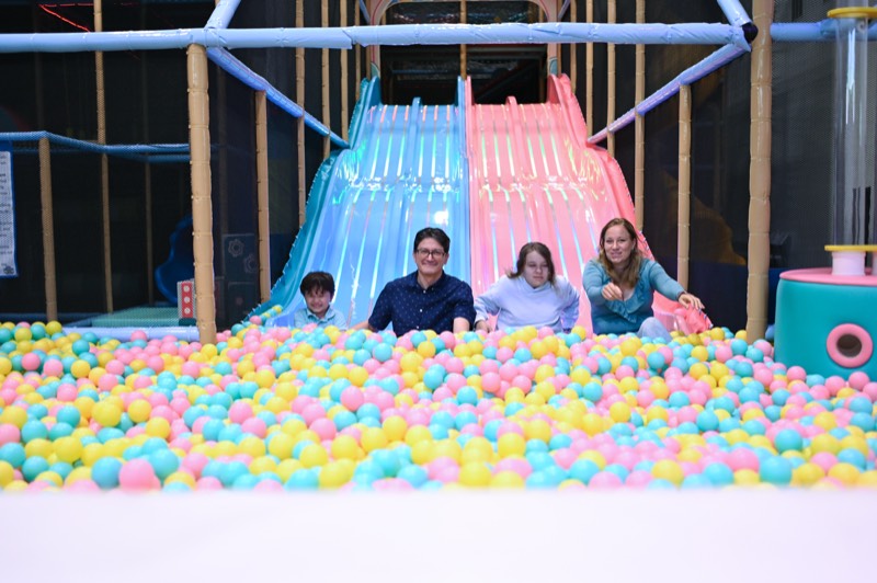 A family sliding down into the ball pit